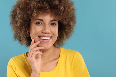 Photo of Woman with clean teeth smiling on light blue background, space for text