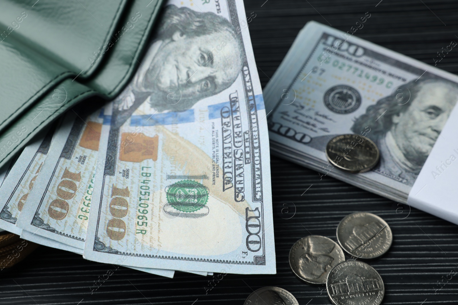 Photo of Dollar banknotes, coins and wallet on black wooden table, closeup. Money exchange