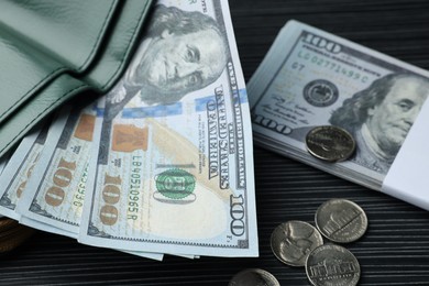 Photo of Dollar banknotes, coins and wallet on black wooden table, closeup. Money exchange