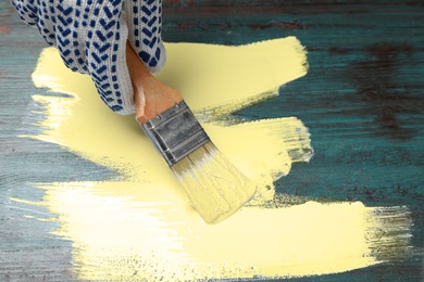 Photo of Person painting teal wooden surface yellow, closeup