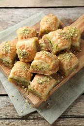 Photo of Delicious fresh baklava with chopped nuts on wooden table, above view. Eastern sweets