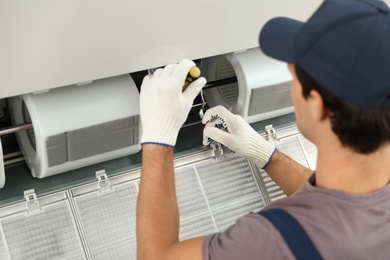 Photo of Male technician repairing air conditioner indoors