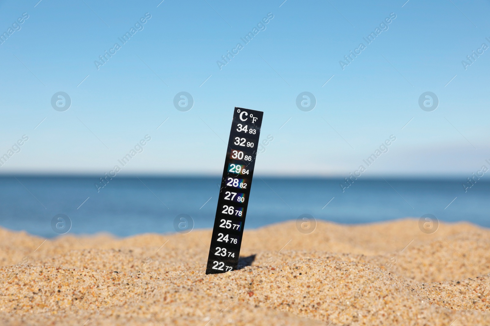 Photo of Black weather thermometer in sand near sea