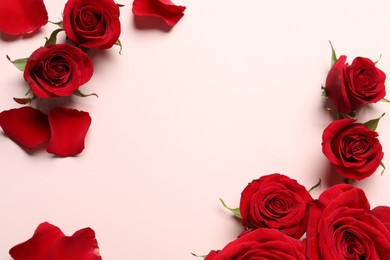 Photo of Beautiful red roses and petals on pale pink background, flat lay. Space for text