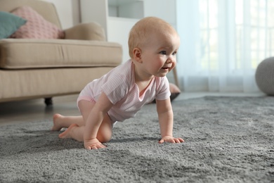 Photo of Cute little baby crawling on soft carpet indoors