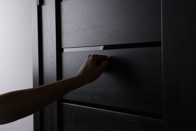 Woman knocking on door indoors, closeup view