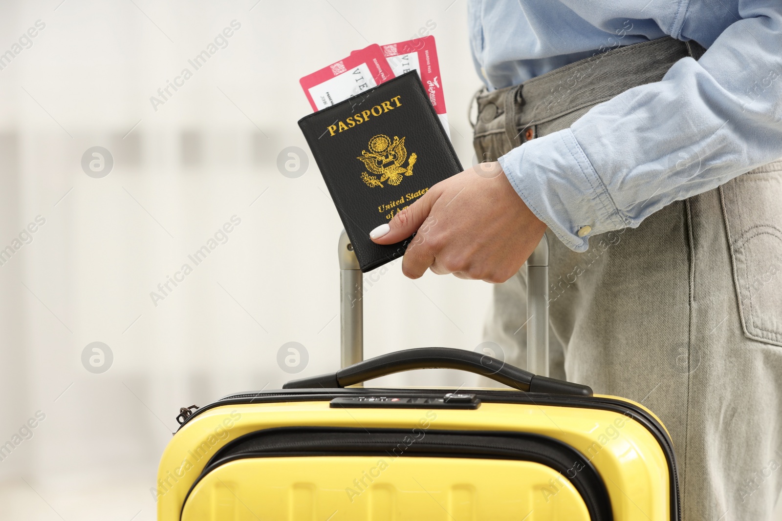 Photo of Woman with suitcase, passport and tickets on blurred background, closeup. Space for text