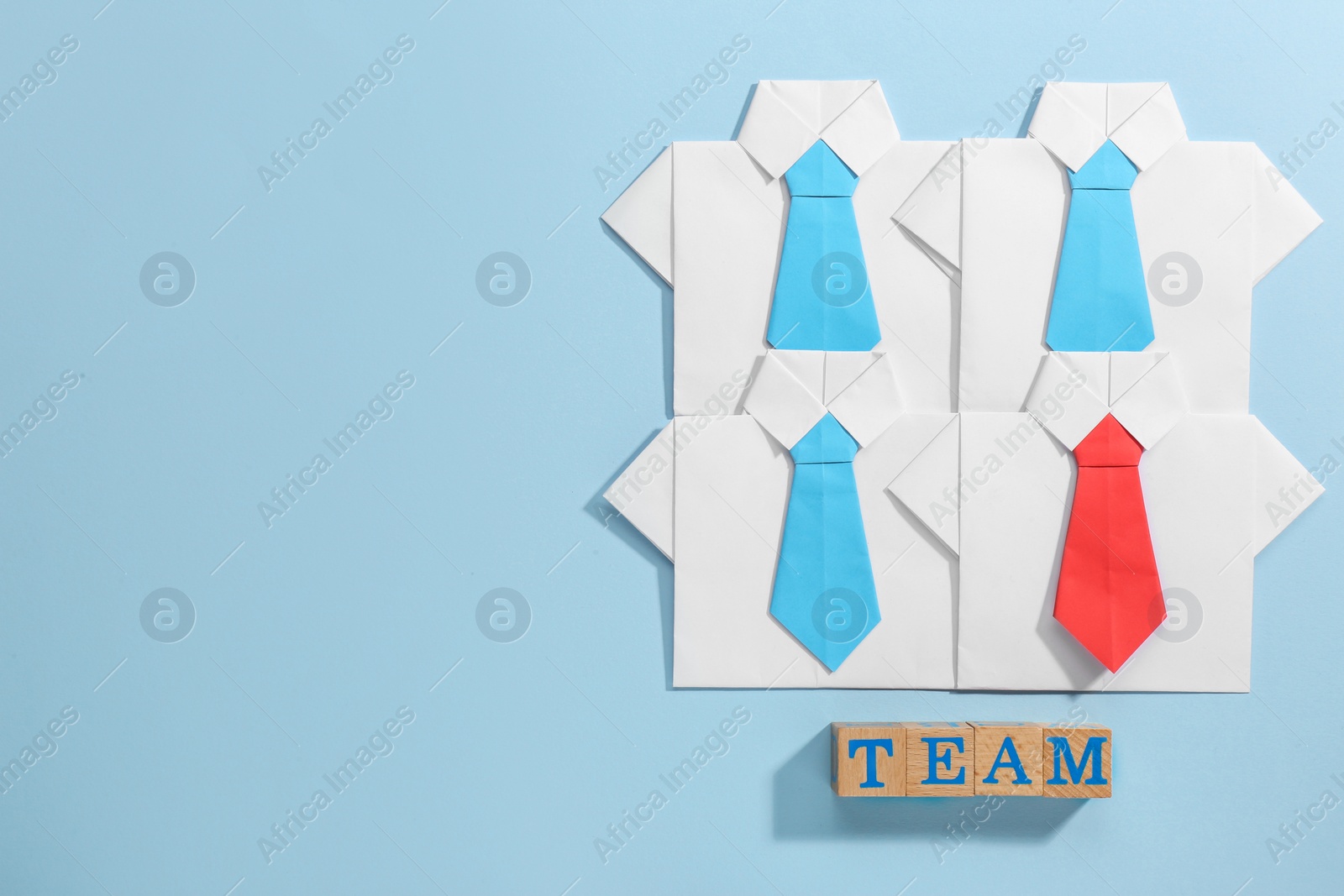 Photo of Many paper shirts and word Team on light blue background, flat lay with space for text. Recruiter searching employee