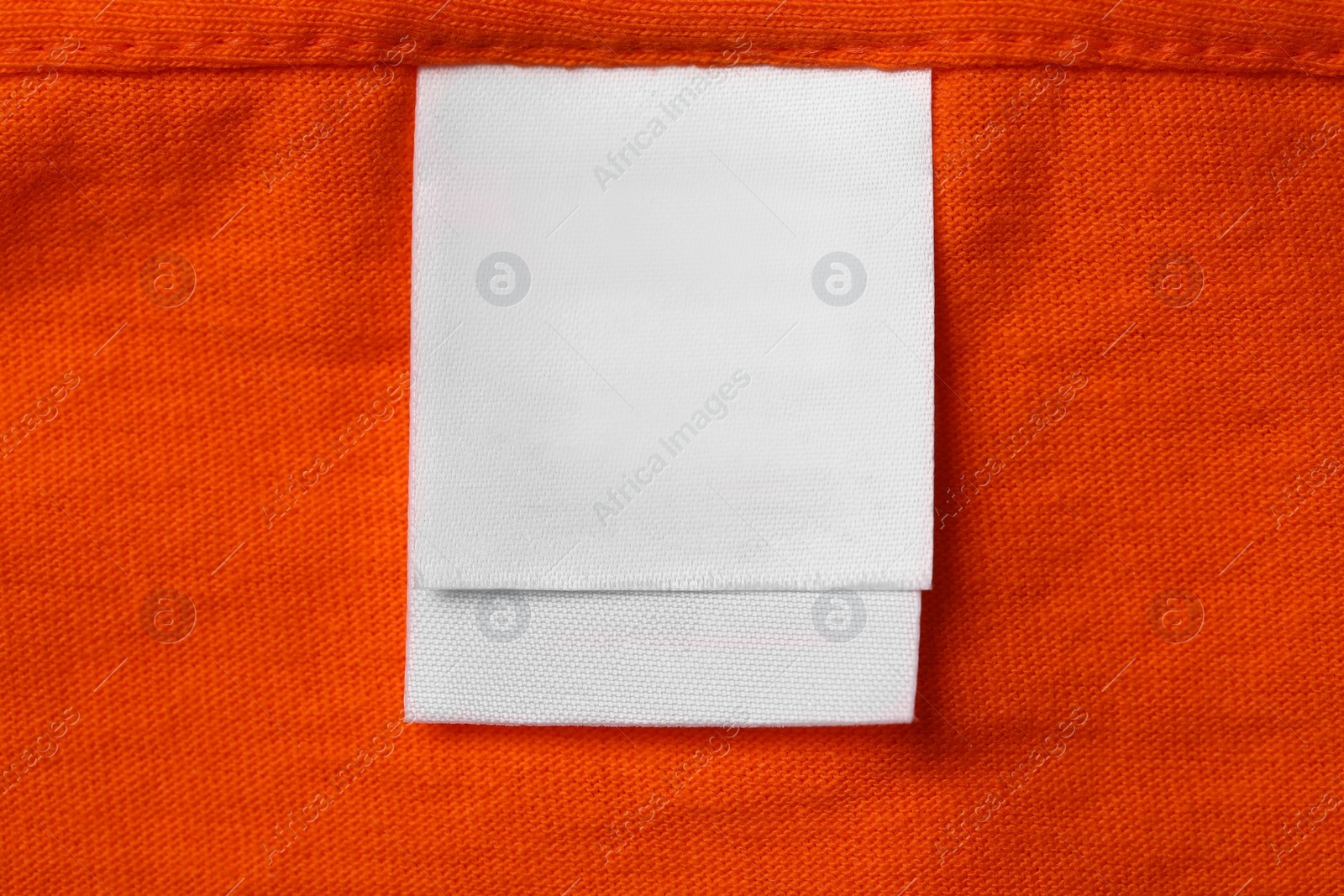 Photo of Clothing label on orange garment, top view