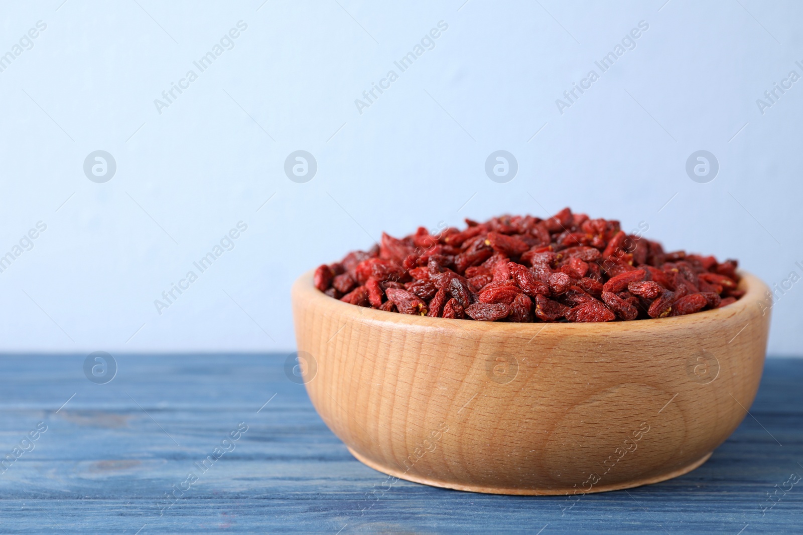 Photo of Dry goji berries on blue wooden table, closeup