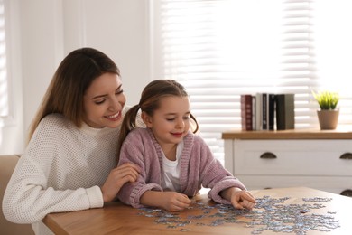 Photo of Woman and his little daughter playing with puzzles at home