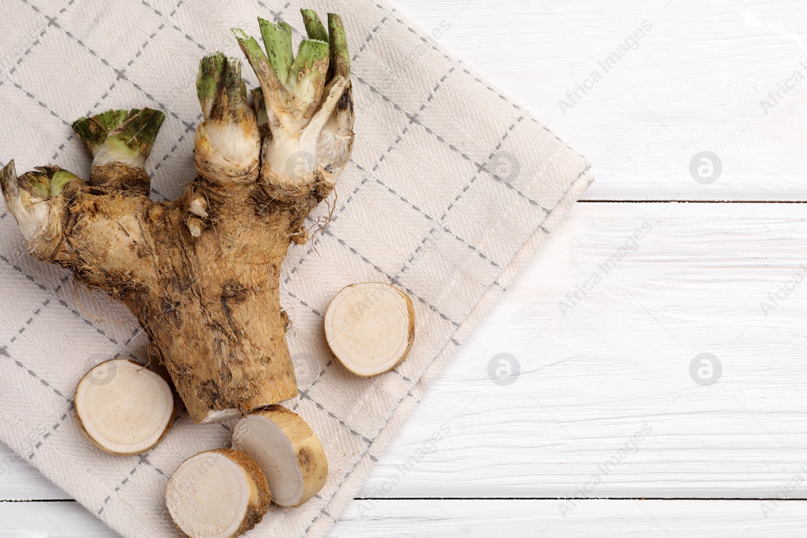 Photo of Cut horseradish root on white wooden table, top view. Space for text