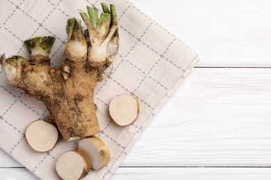 Photo of Cut horseradish root on white wooden table, top view. Space for text