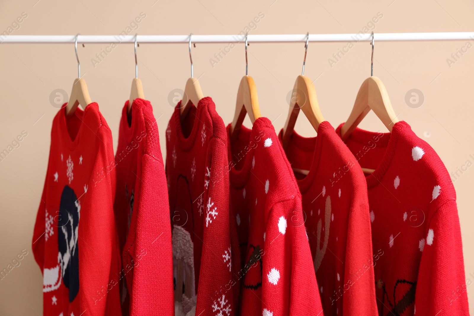 Photo of Rack with different Christmas sweaters on beige background