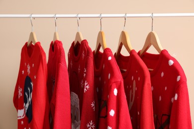 Rack with different Christmas sweaters on beige background