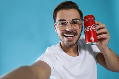 MYKOLAIV, UKRAINE - NOVEMBER 28, 2018: Young man taking selfie with Coca-Cola can on color background