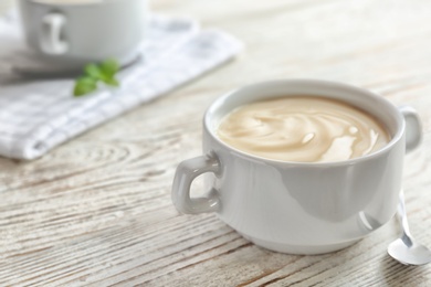 Photo of Bowl with vanilla pudding on wooden background