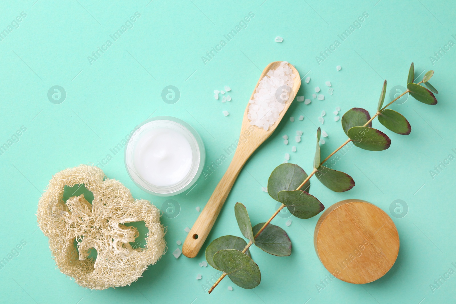 Photo of Jar of cream, body care products and eucalyptus branch on turquoise background, flat lay