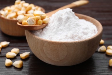 Photo of Bowl of corn starch and kernels on dark wooden table, closeup