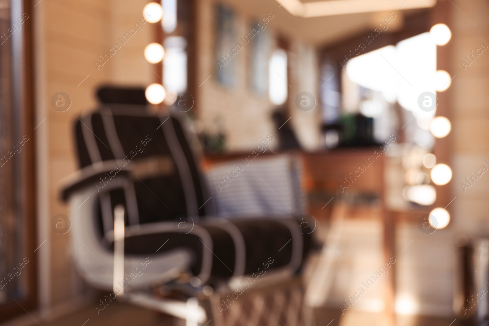 Photo of Blurred view of stylish hairdresser's workplace with professional armchair in barbershop