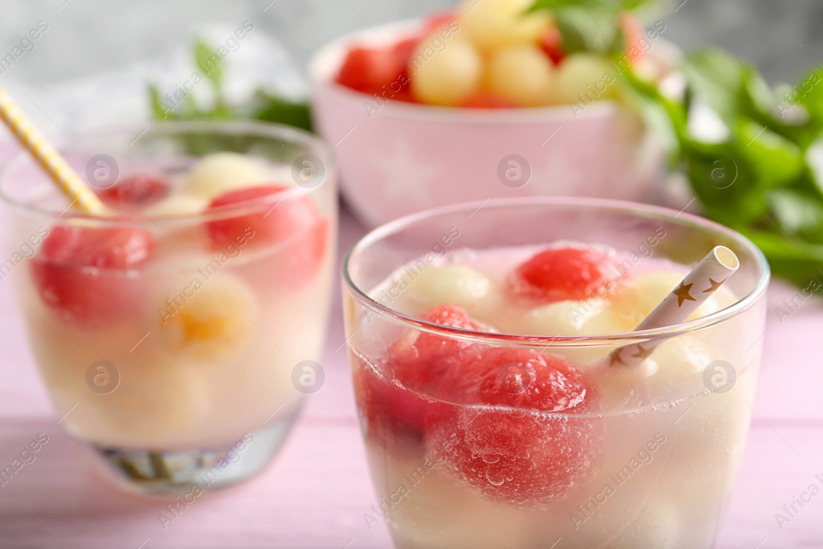 Photo of Glasses of melon and watermelon ball cocktail on pink wooden table, closeup