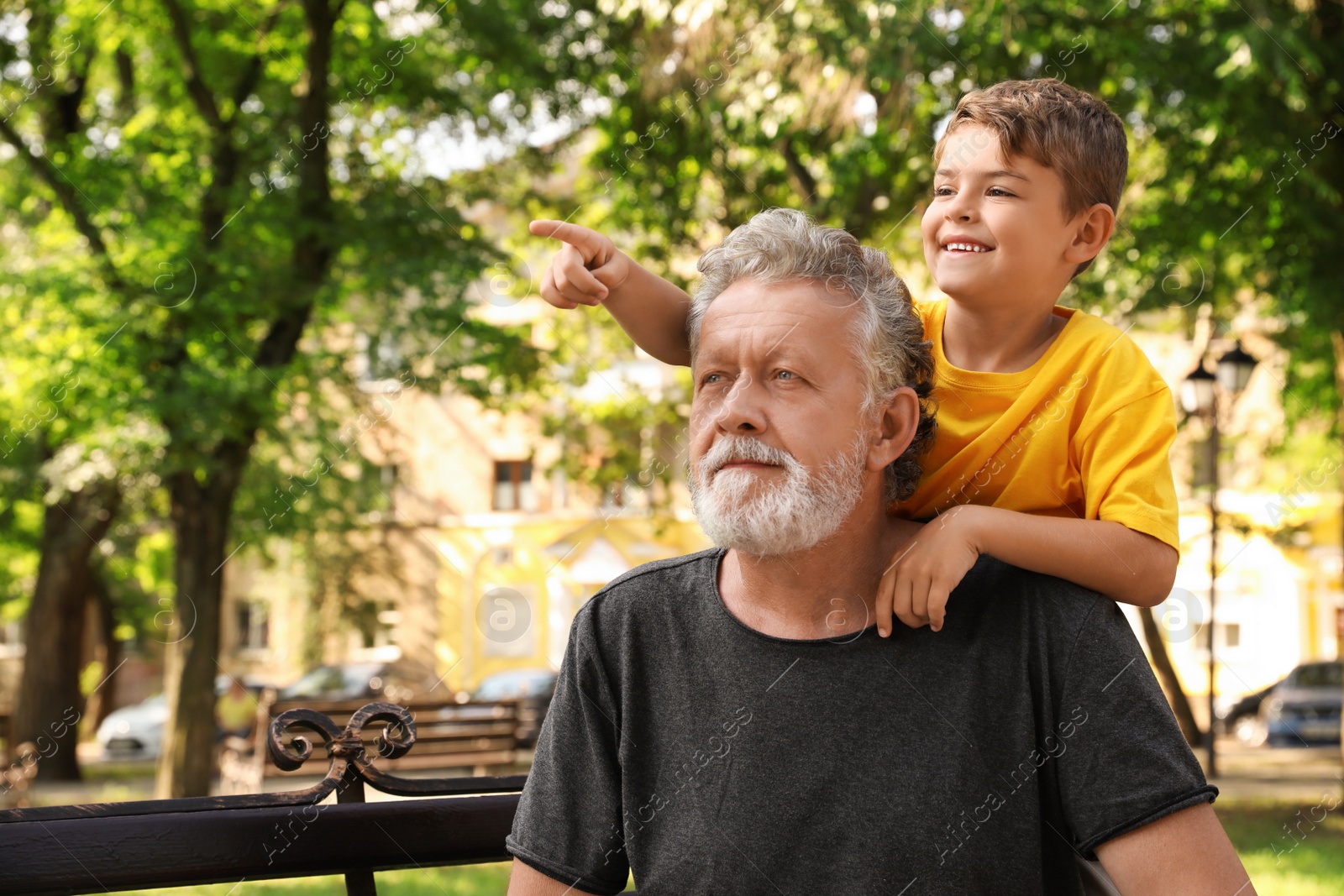 Photo of Senior man with his little grandson resting together in park