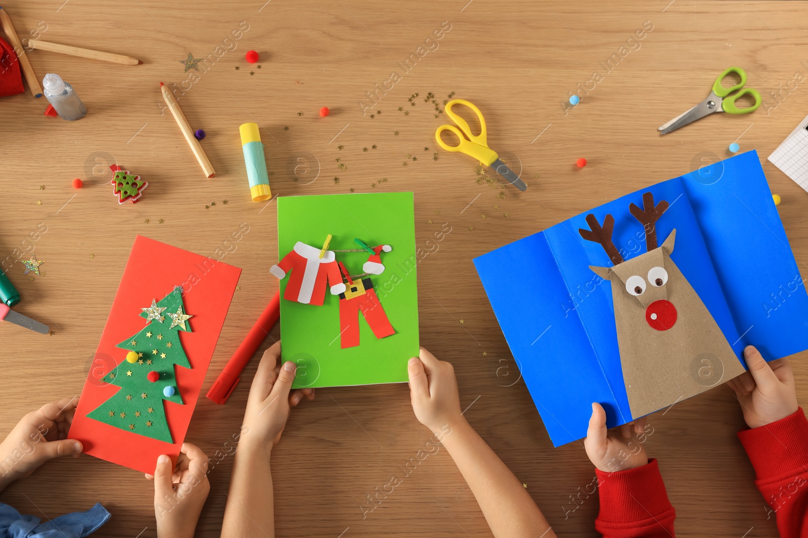 Photo of Little children making beautiful Christmas greeting cards at table, top view