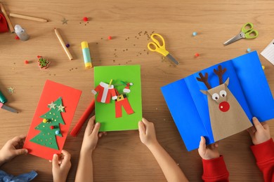 Photo of Little children making beautiful Christmas greeting cards at table, top view