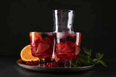 Photo of Delicious Red Sangria and ingredients on black table