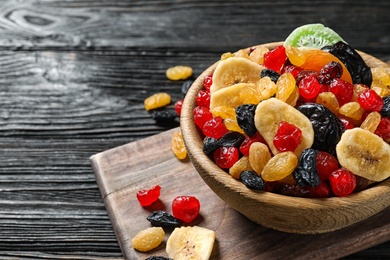 Photo of Bowl with different dried fruits on wooden background, space for text. Healthy lifestyle