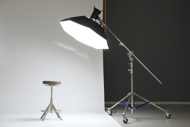 Photo of White photo background, stool and professional lighting equipment in modern studio