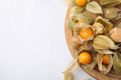 Ripe physalis fruits with calyxes on white table, top view. Space for text