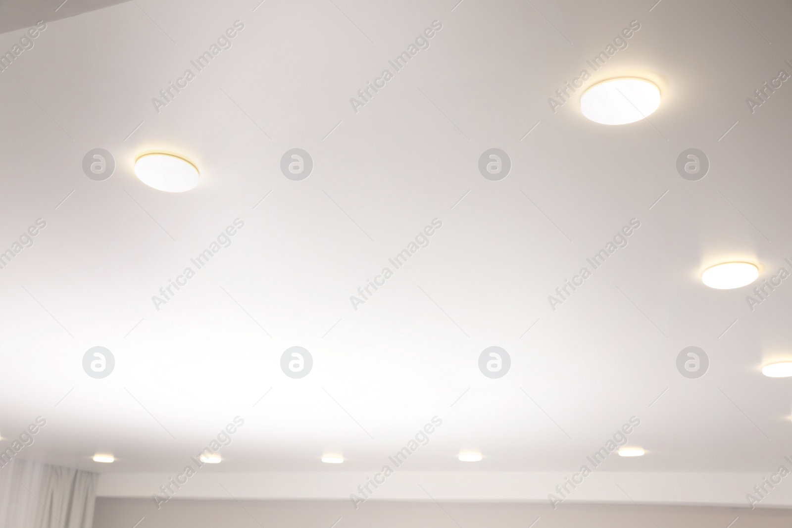 Photo of White stretch ceiling with spot lights in room, low angle view