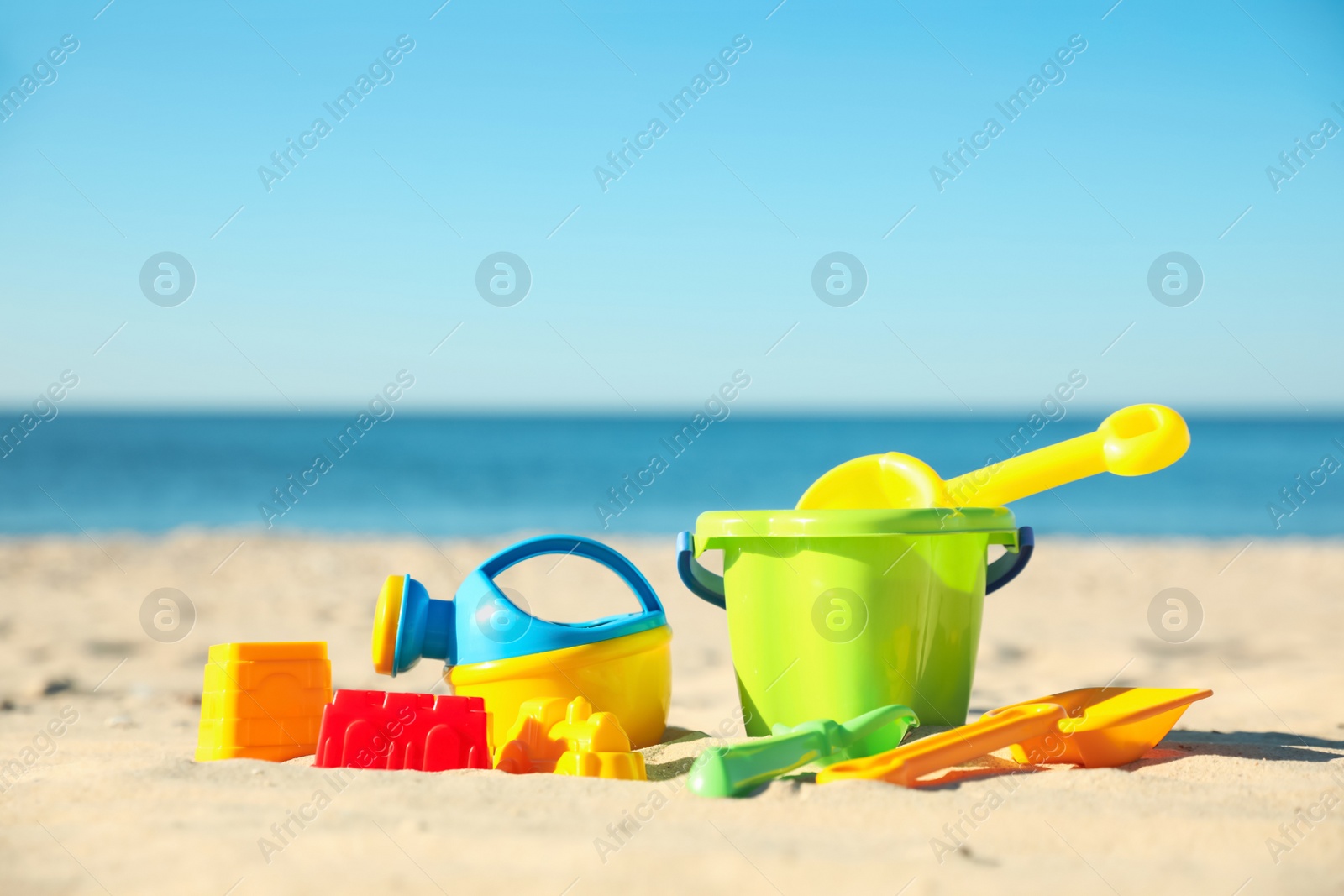 Photo of Different child plastic toys on sandy beach. Space for text