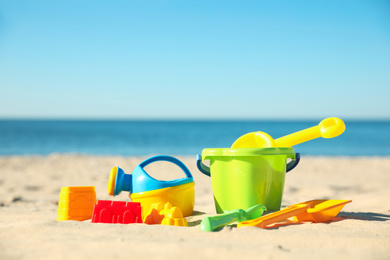 Photo of Different child plastic toys on sandy beach. Space for text