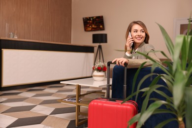 Beautiful woman talking on phone while waiting in hotel hall