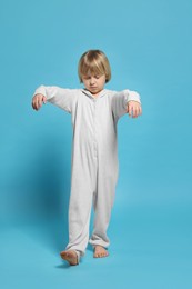 Photo of Boy in pajamas sleepwalking on light blue background