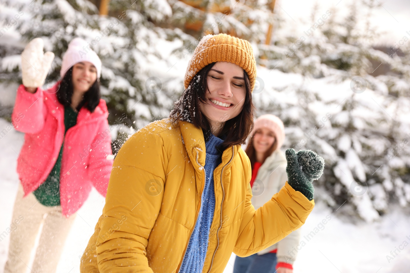 Photo of Happy friends playing snowballs outdoors. Winter vacation