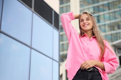 Portrait of beautiful young woman near building outdoors, low angle view. Space for text