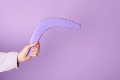 Photo of Woman holding boomerang on lilac background, closeup