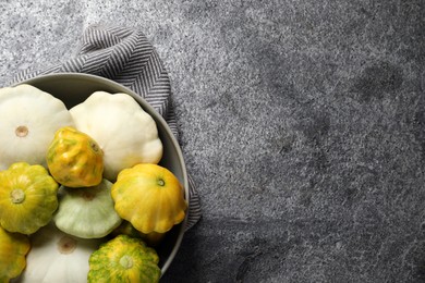 Fresh ripe pattypan squashes in bowl on grey table, top view. Space for text