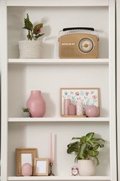 Photo of Stylish shelves with decorative elements and houseplants near white wall. Interior design