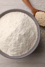 Photo of Ceramic bowl with quinoa flour and seeds on wooden table, top view