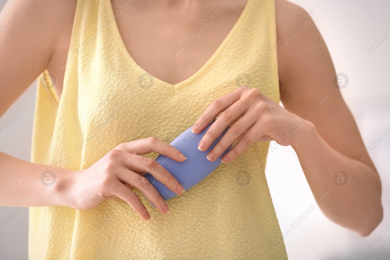 Photo of Young woman holding bottle with hand cream, closeup