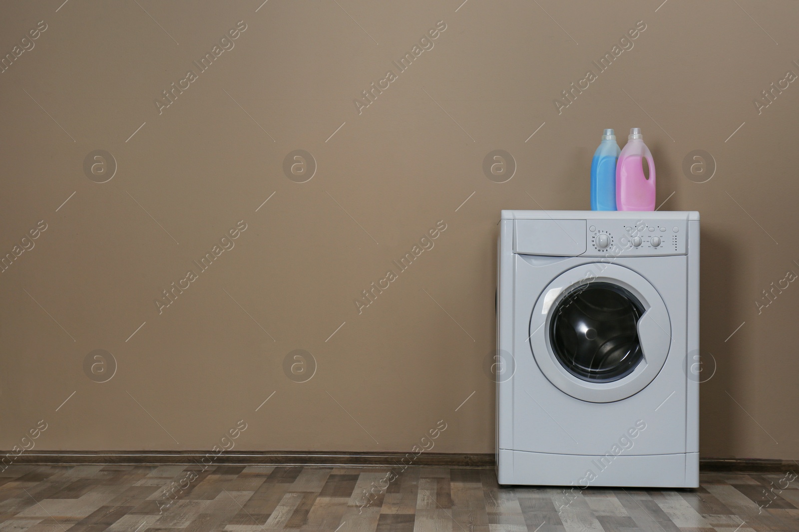 Photo of Modern washing machine with detergents near beige wall, space for text. Laundry day