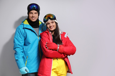 Photo of Couple wearing stylish winter sport clothes on light grey background. Space for text