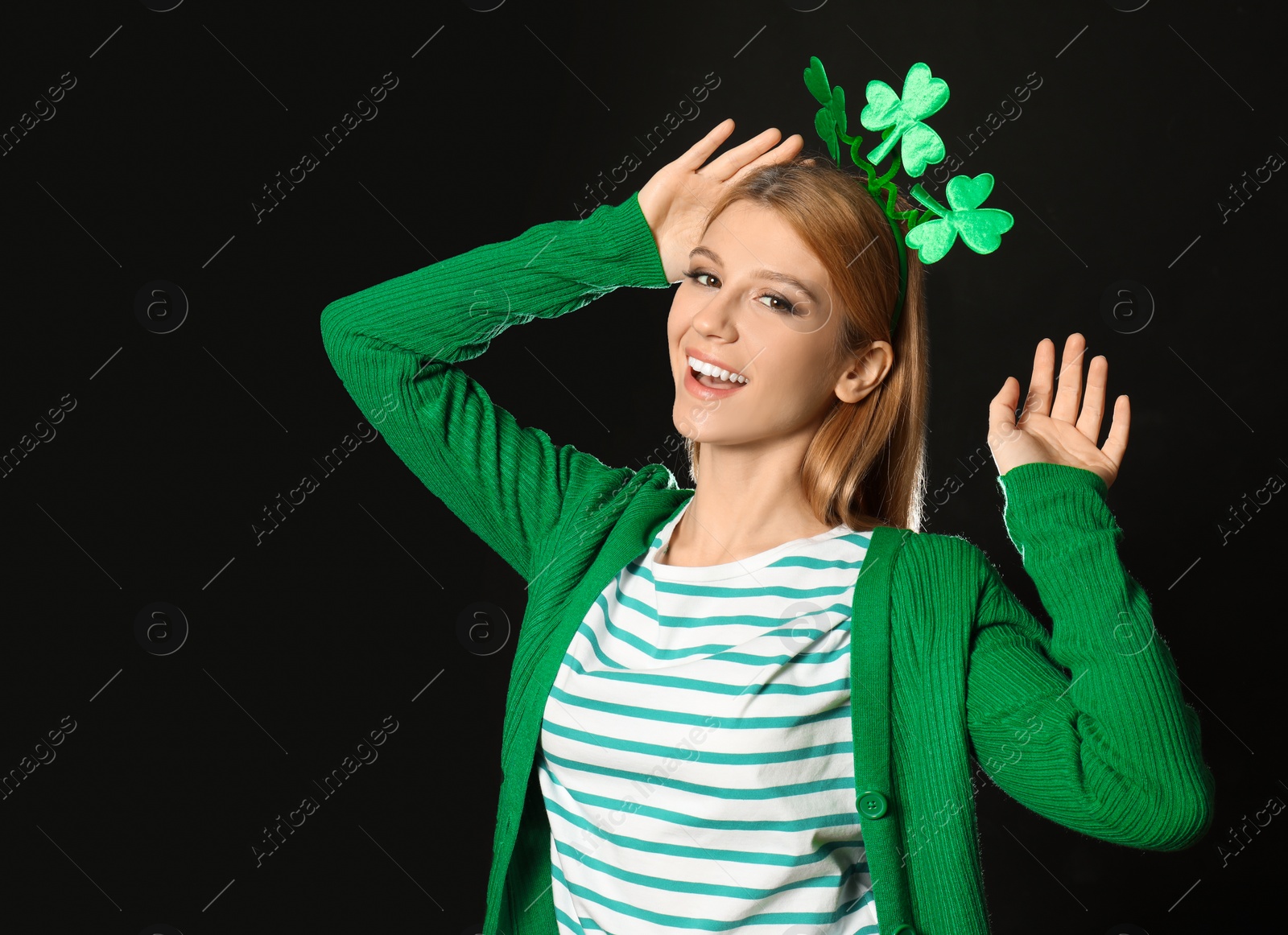 Photo of Young woman with clover headband on black background. St. Patrick's Day celebration