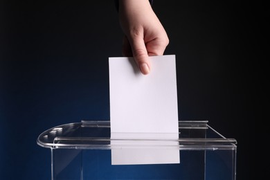 Woman putting her vote into ballot box on dark blue background, closeup
