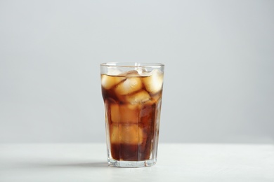 Photo of Glass of refreshing cola with ice cubes on table