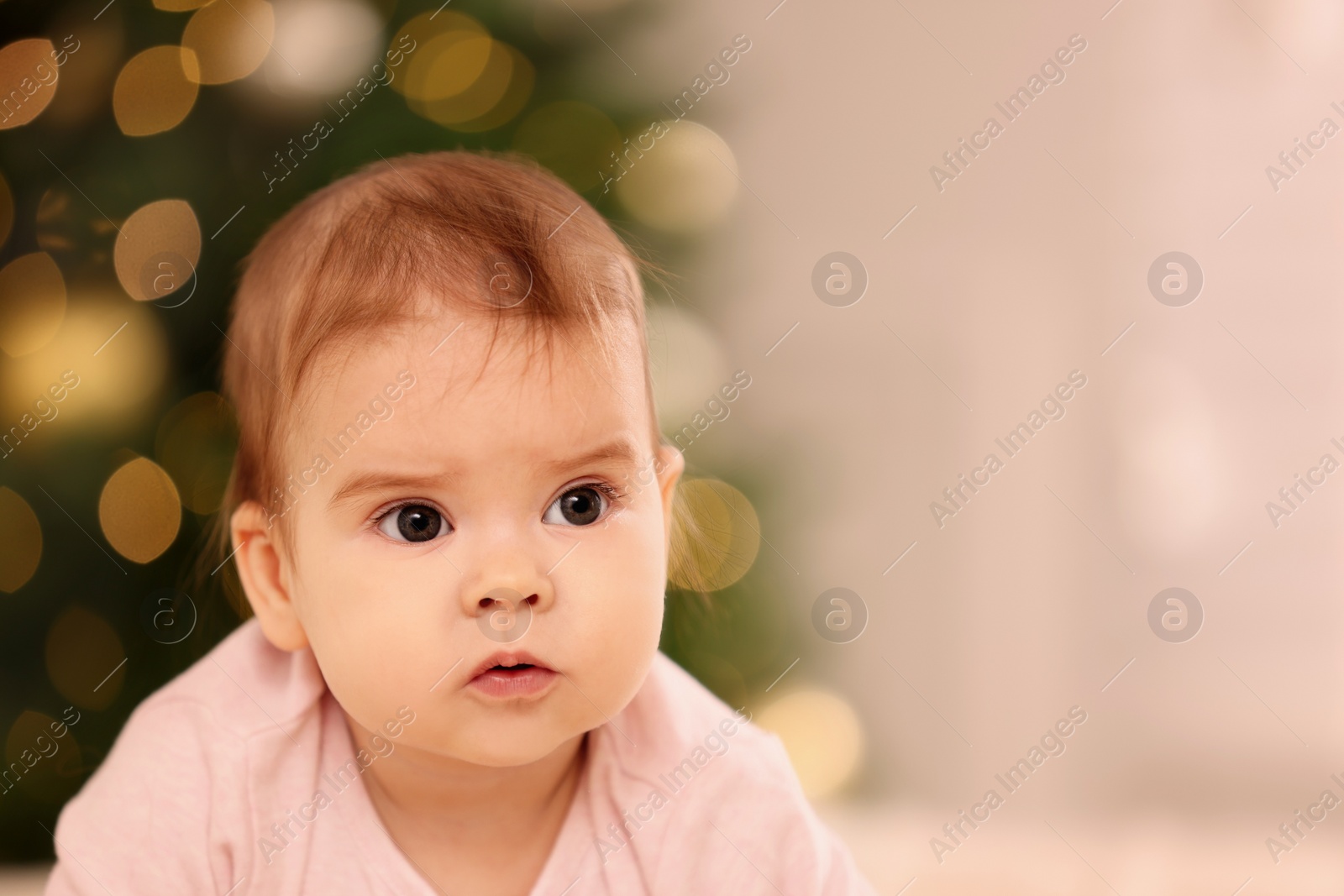 Photo of Portrait of cute little baby against blurred festive lights, space for text. Winter holiday